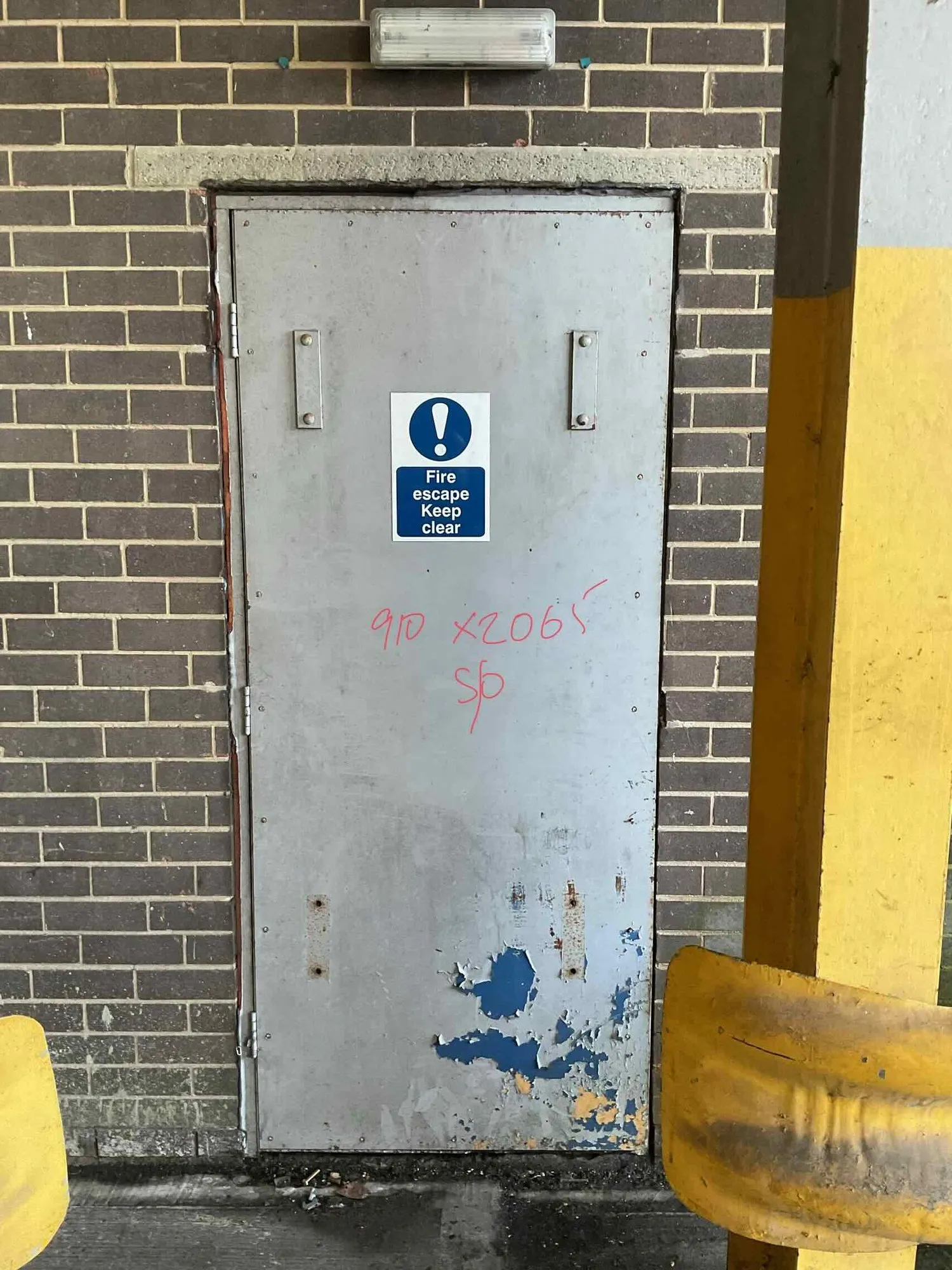 Old galvanised steel exit door, damaged and past its life, before replacement