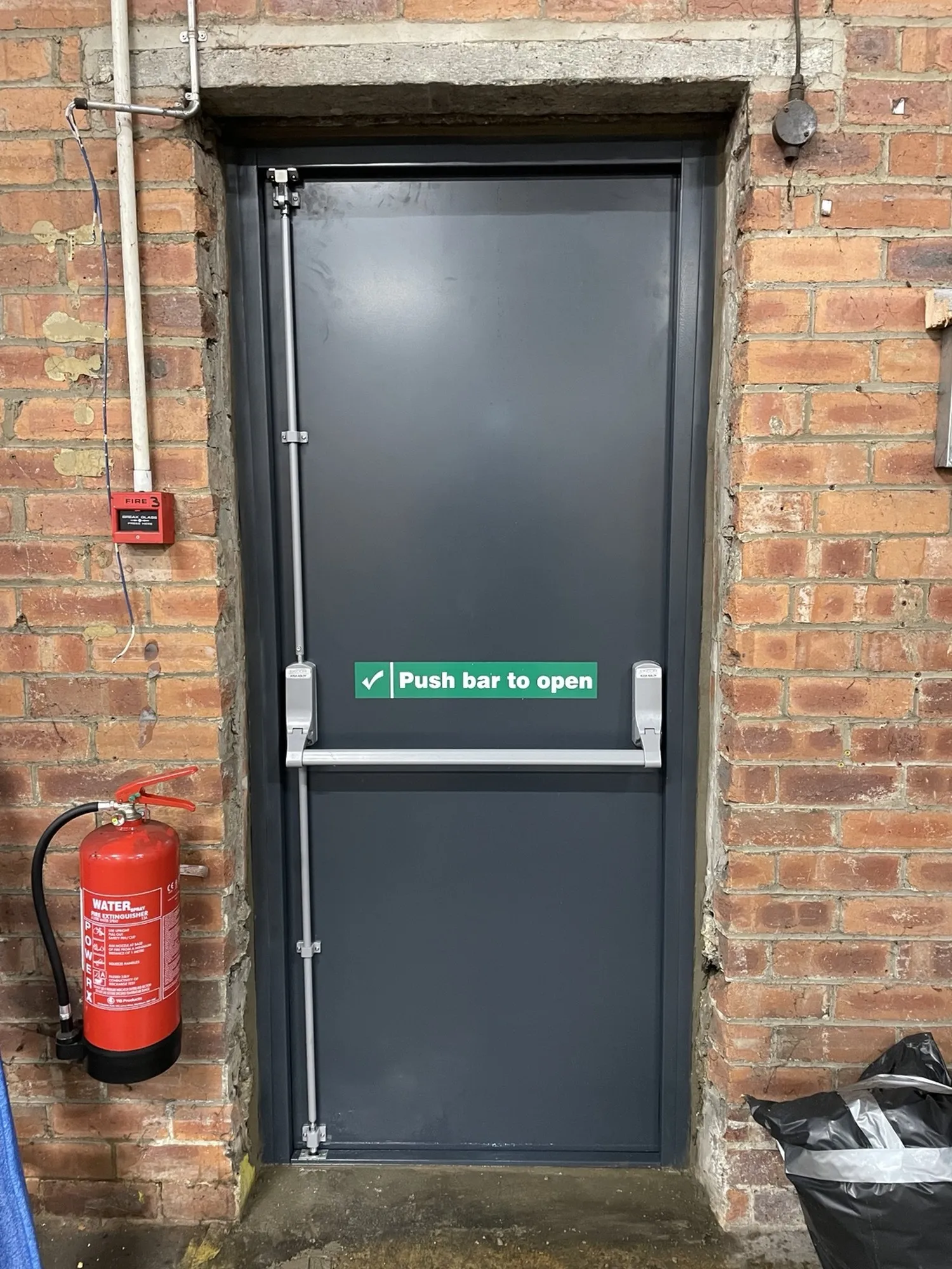 Inside view of the fitted steel exit door showing the push-bar panic hardware and 'Push bar to open' signage